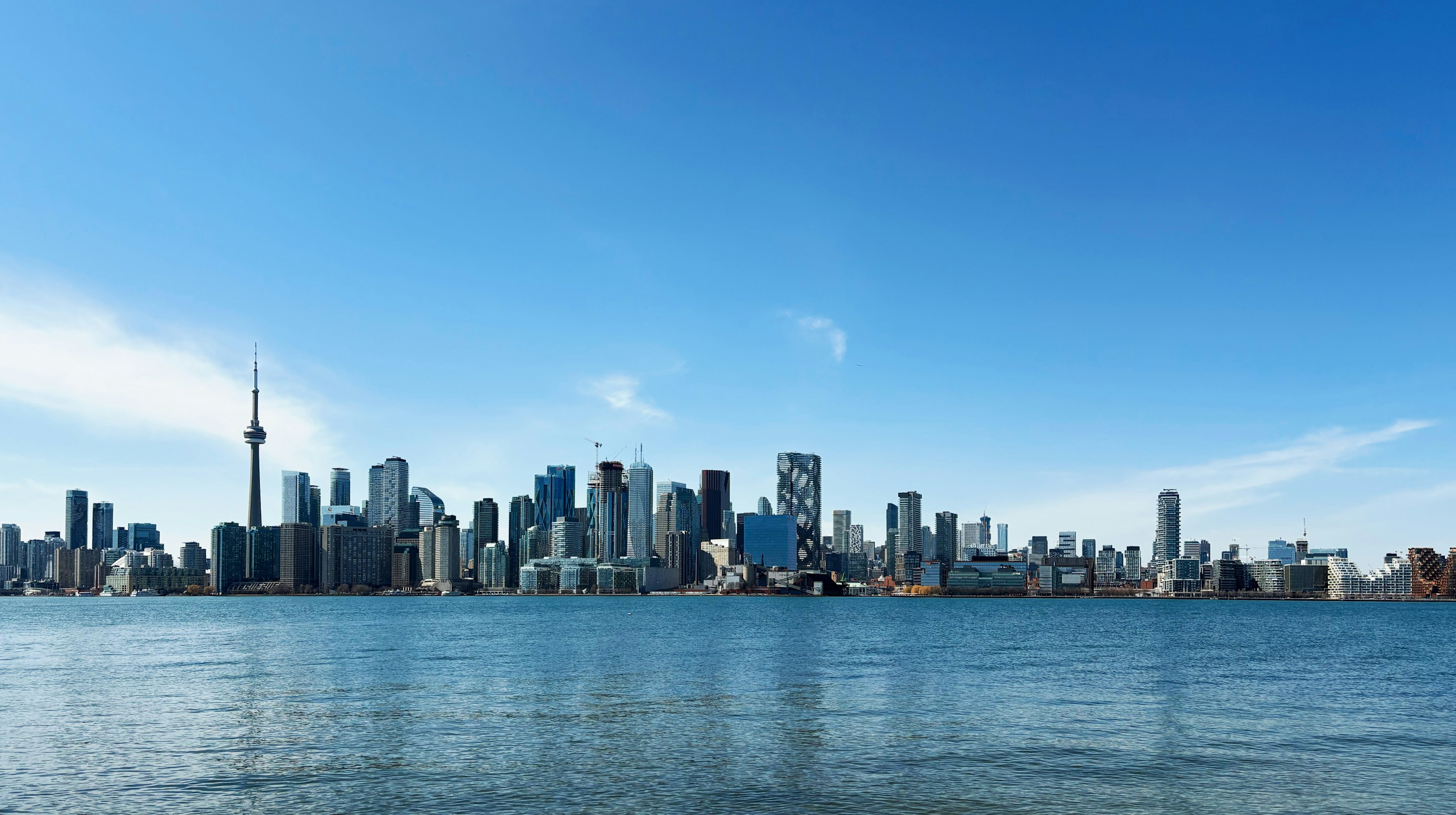 The Toronto skyline and CN Tower across the blue water of Lake Ontario